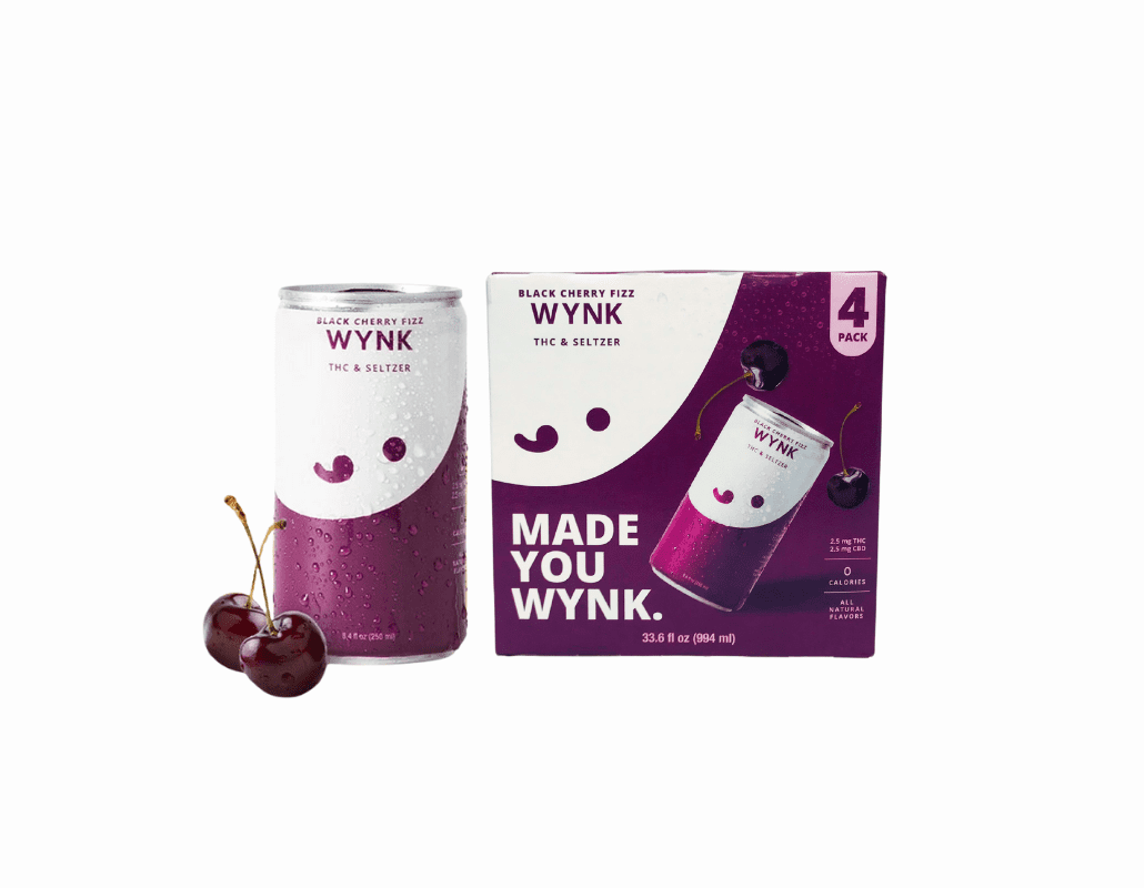 A can and a four-pack box of WYNK Black Cherry Fizz THC & Seltzer, with fresh cherries placed beside the can. The packaging is purple and white with the text 'MADE YOU WYNK' visible on the box.